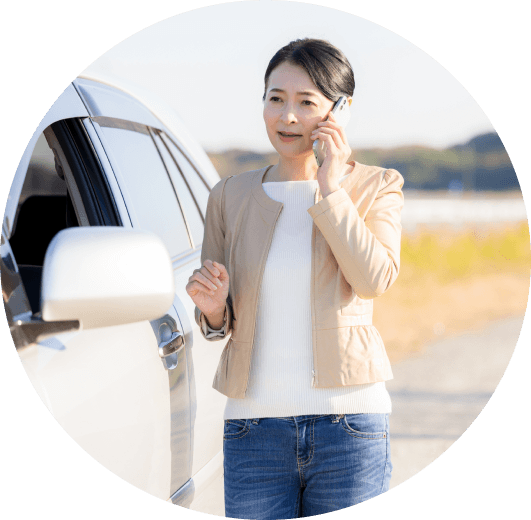 自動車の横で電話する女性